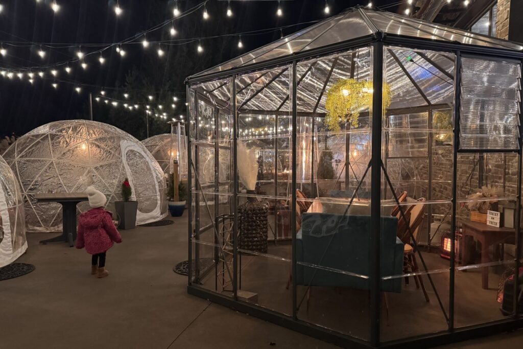 Outdoor dining domes lit with string lights.