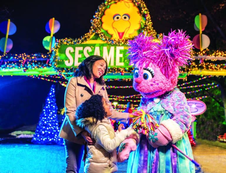 Children with Sesame Street characters at festive holiday event.