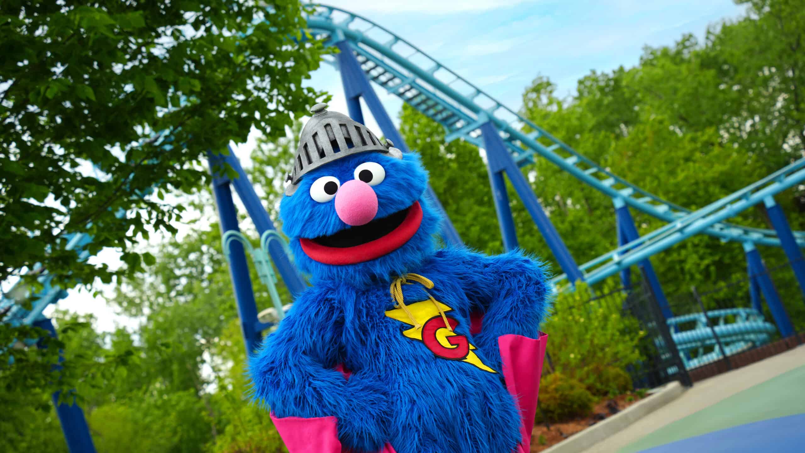 Sesame Place Philadelphia mascot in front of roller coaster ride.