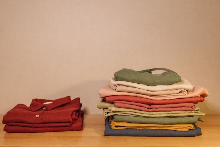 Neatly folded colorful clothes on a wooden table, showcasing texture and style.